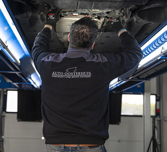 Monteur Auto Oosterhuis Heiligerlee sleutelt aan de onderkant van een auto
